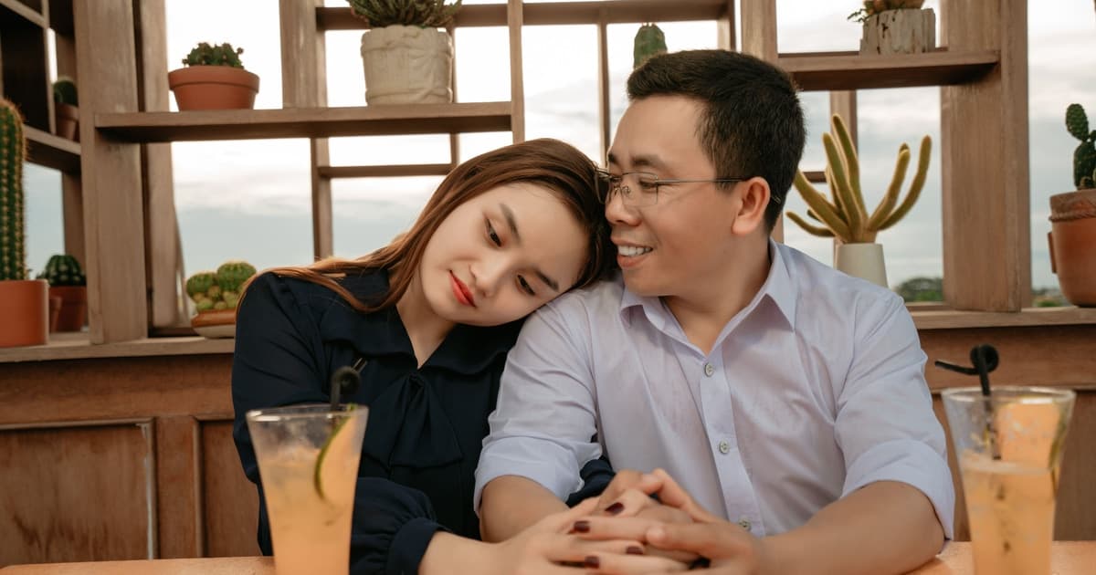 카페에서 손을 맞잡고 어깨에 기대어 앉은 커플